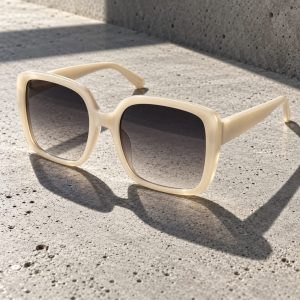 Occhiali da sole oversize Scirocco in acetato avorio con lenti grigie sfumate su cemento