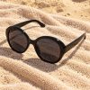 Occhiali da sole oversize rotondi Darsena in acetato nero su telo da spiaggia