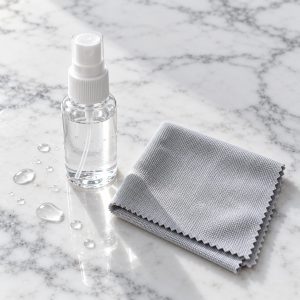Kit pulizia lenti con spray da 30 ml e panno in microfibra su marmo